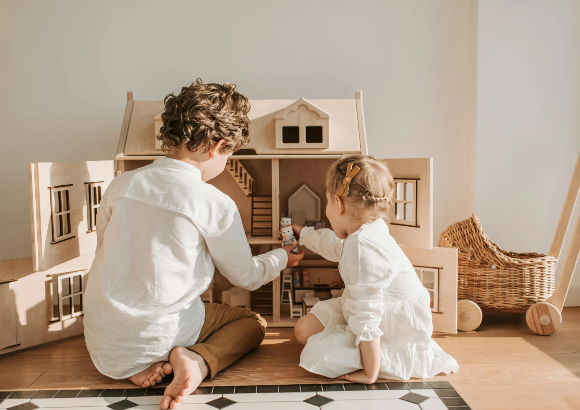 Två barn som leker tillsammans med ett dockhus